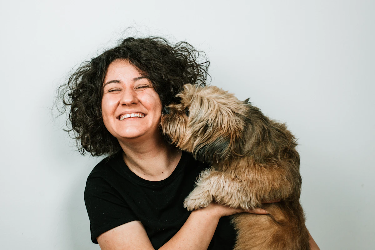 A woman smiling as she holds a small Shih Tzu puppy